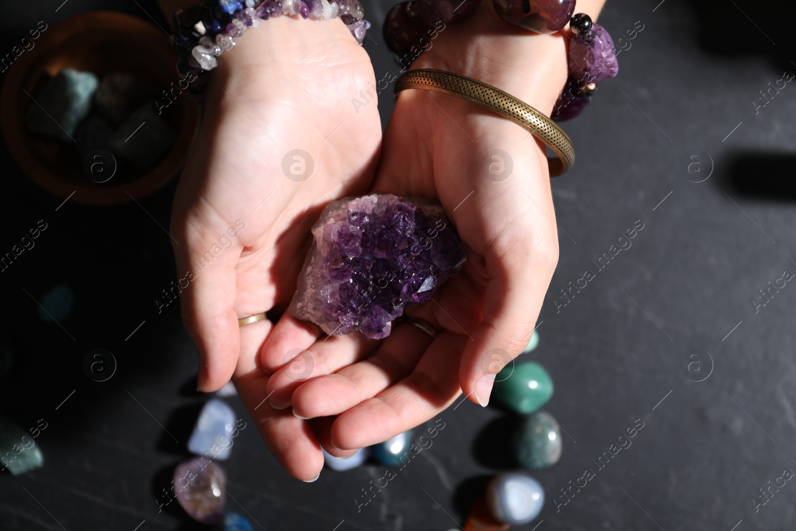 Photo of Woman with healing stones at black table, closeup