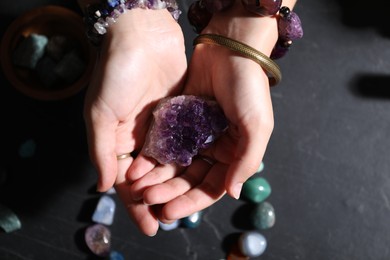 Photo of Woman with healing stones at black table, closeup
