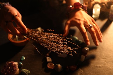 Photo of Woman doing ritual with healing stones at dark table, closeup