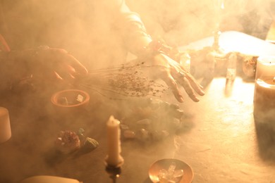 Photo of Woman doing ritual with healing stones at dark table, closeup