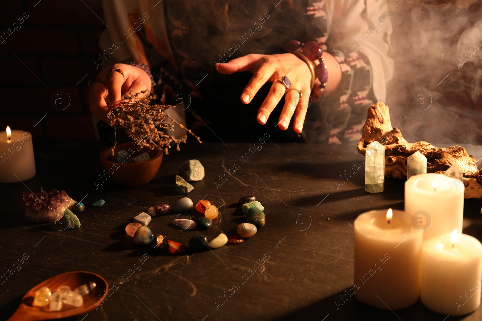 Woman doing ritual with healing stones at dark table, closeup Photo of Woman doing ritual with healing stones at dark table, closeup