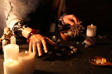 Photo of Woman doing ritual with healing stones at dark table, closeup