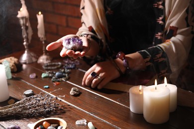 Photo of Woman doing ritual with healing stones at wooden table, closeup