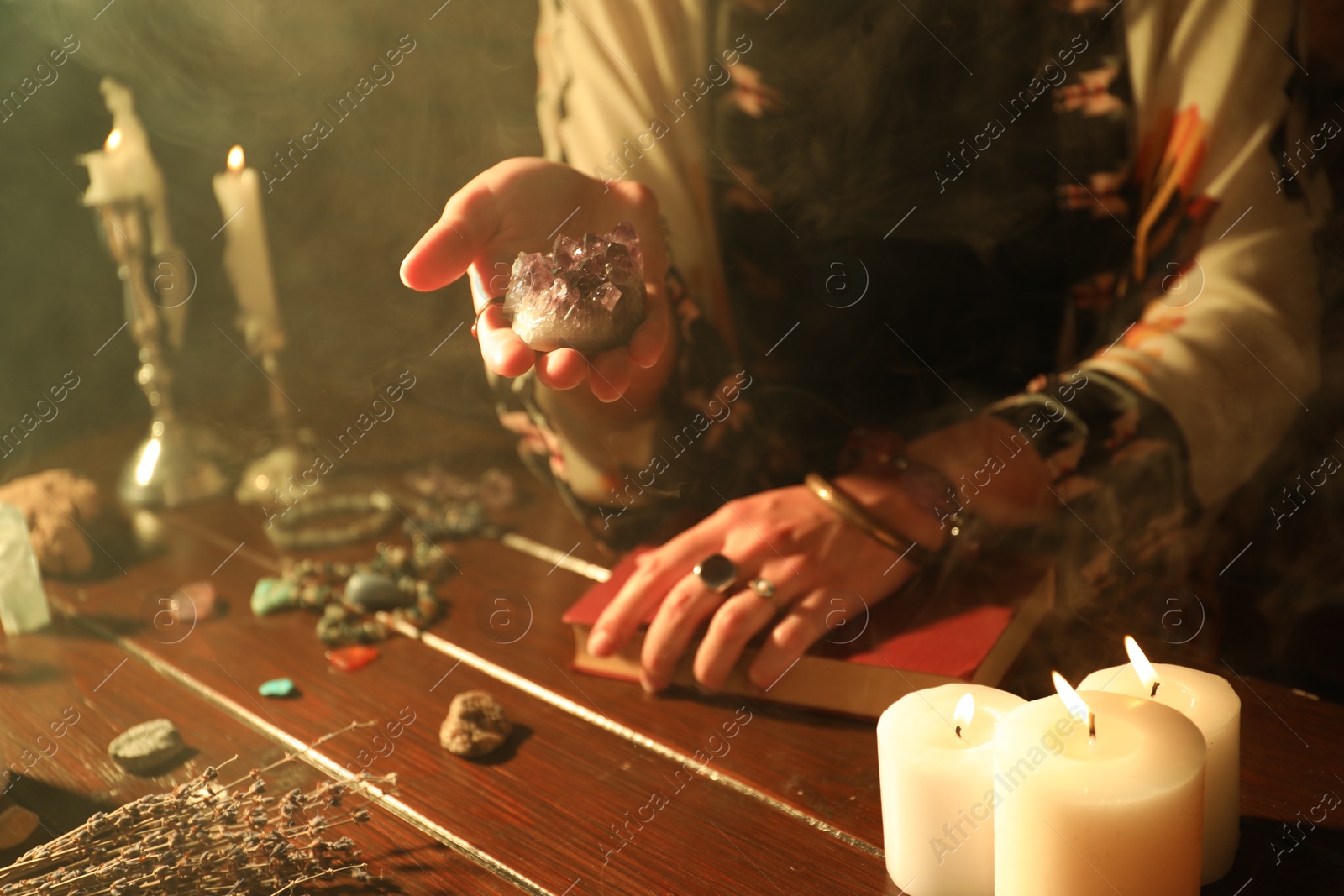 Woman doing ritual with healing stones at wooden table, closeup Photo of Woman doing ritual with healing stones at wooden table, closeup