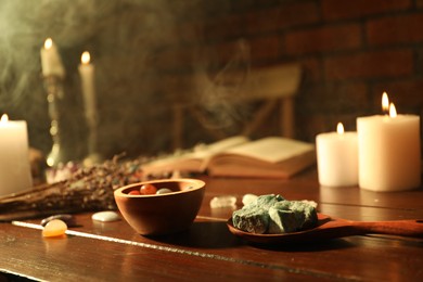 Photo of Healing stones, book, lavender and burning candles on wooden table