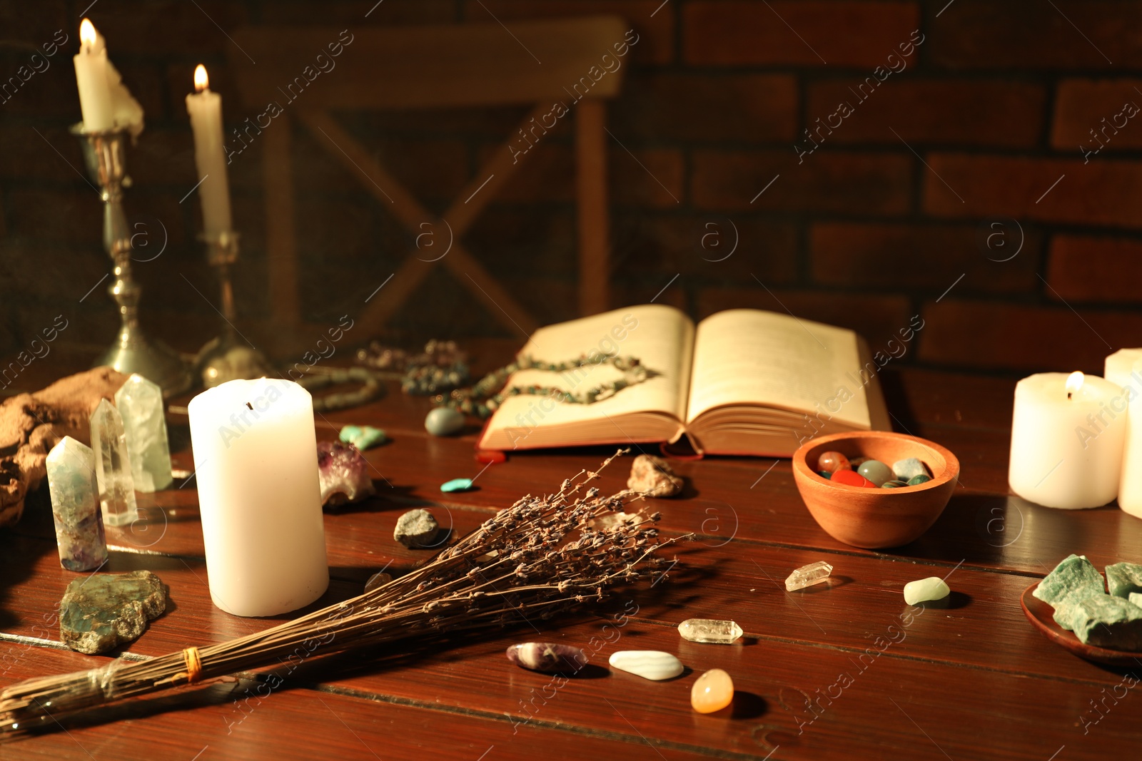 Healing stones, book, lavender and burning candles on wooden table Photo of Healing stones, book, lavender and burning candles on wooden table