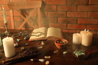 Photo of Healing stones, book, lavender and burning candles on wooden table