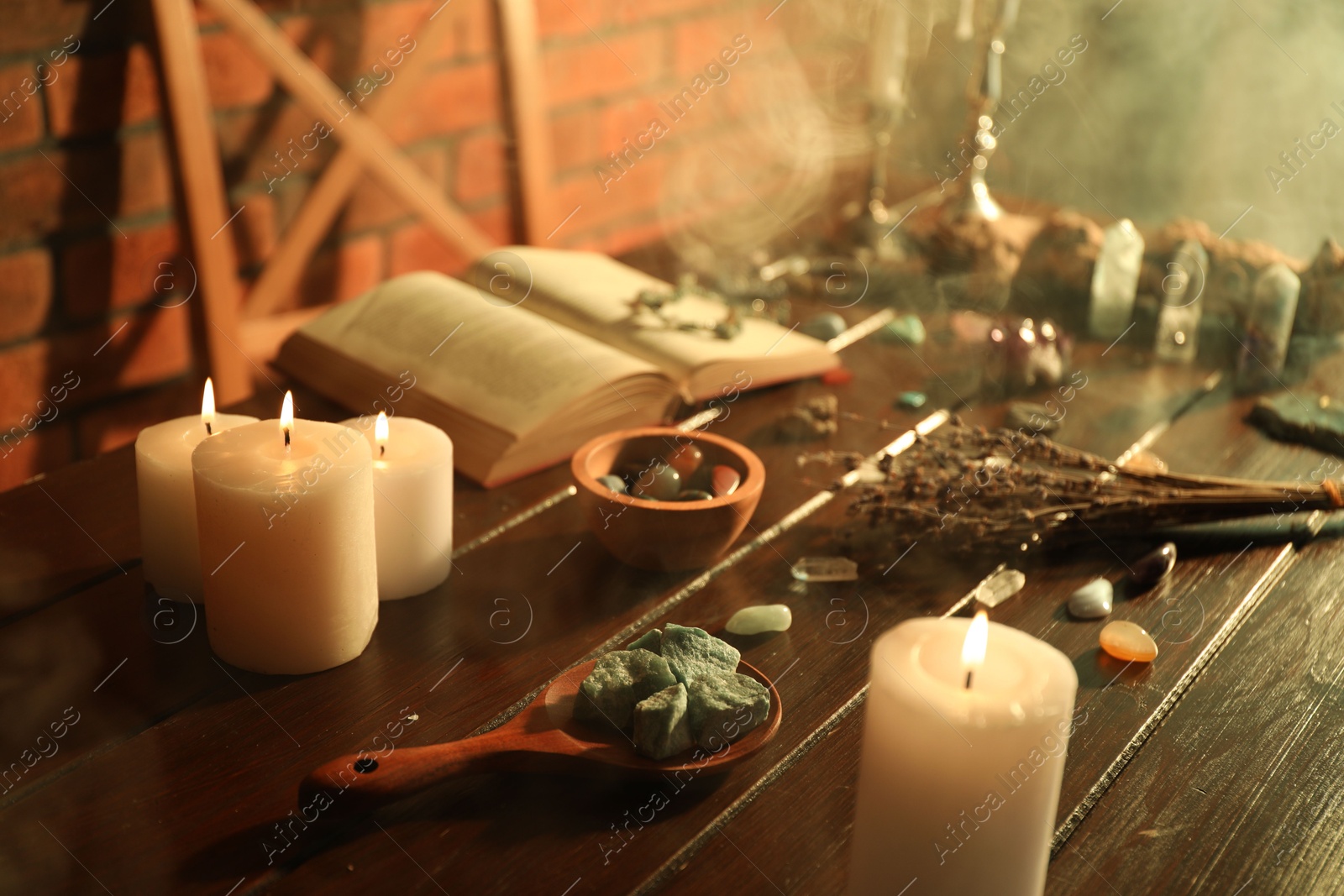 Healing stones, book, lavender and burning candles on wooden table Photo of Healing stones, book, lavender and burning candles on wooden table