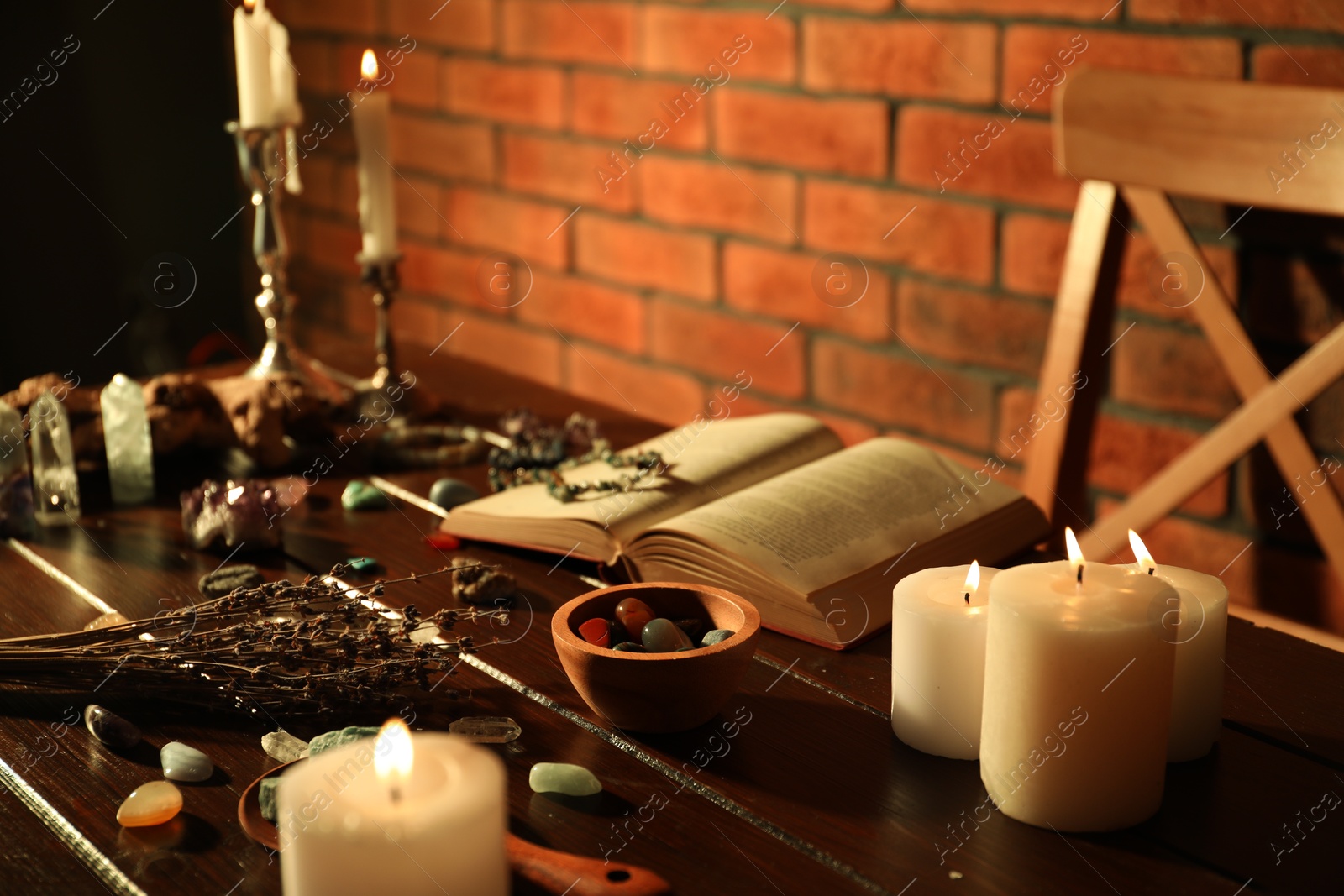 Healing stones, book, lavender and burning candles on wooden table Photo of Healing stones, book, lavender and burning candles on wooden table