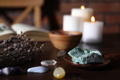 Photo of Healing stones, lavender and burning candles on dark table, closeup
