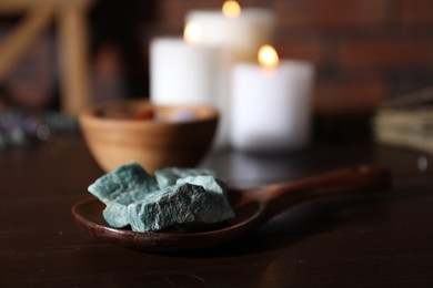 Photo of Healing stones and burning candles on dark table, closeup