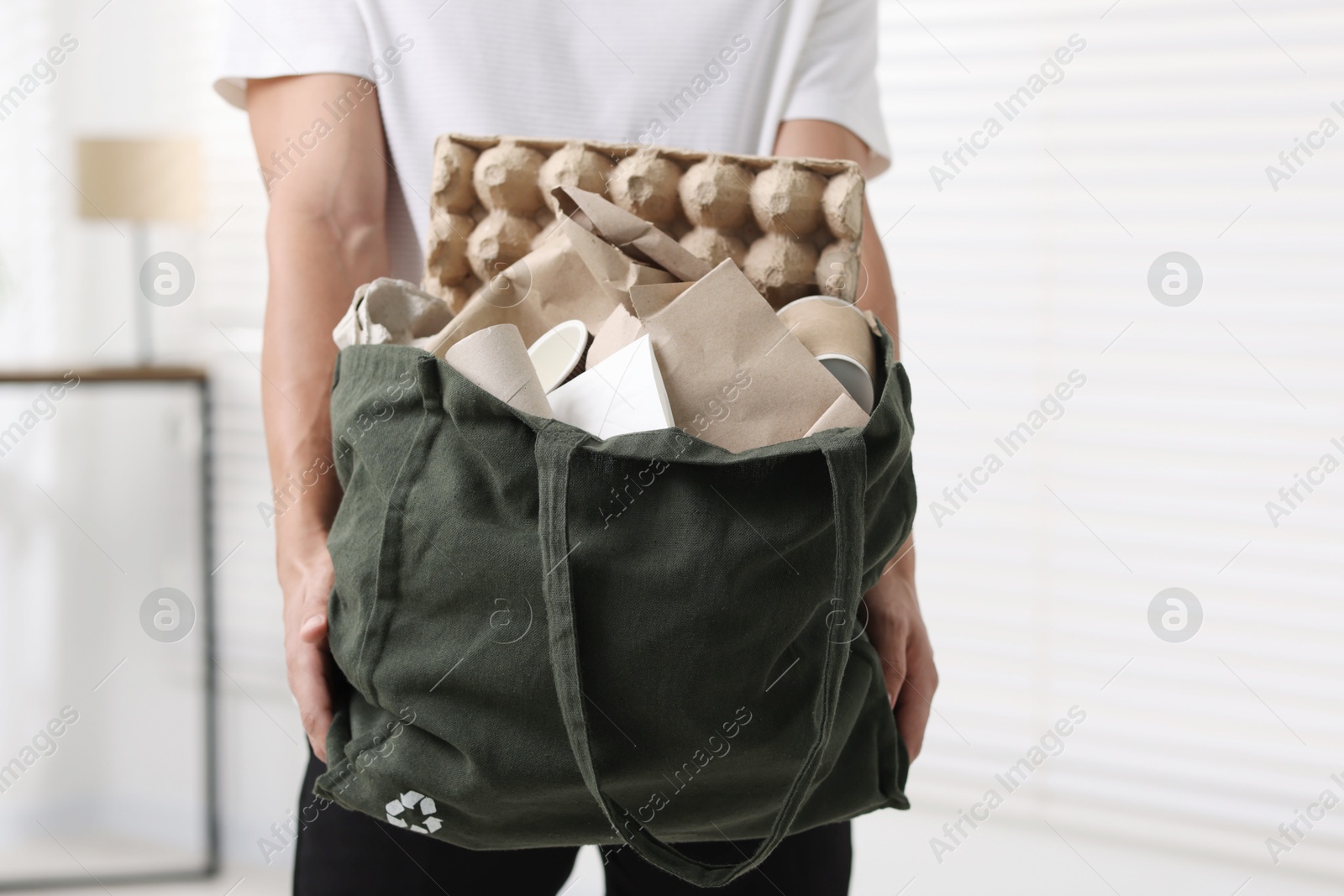 Photo of Recycling. Man with bag full of different waste paper indoors, closeup