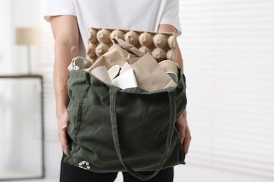 Photo of Recycling. Man with bag full of different waste paper indoors, closeup