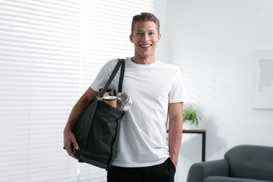 Photo of Recycling. Smiling man with bag full of different waste paper indoors