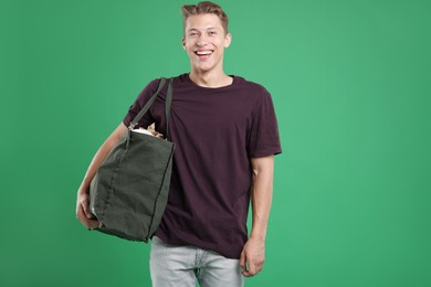 Photo of Recycling. Smiling man with bag full of different waste paper on green background