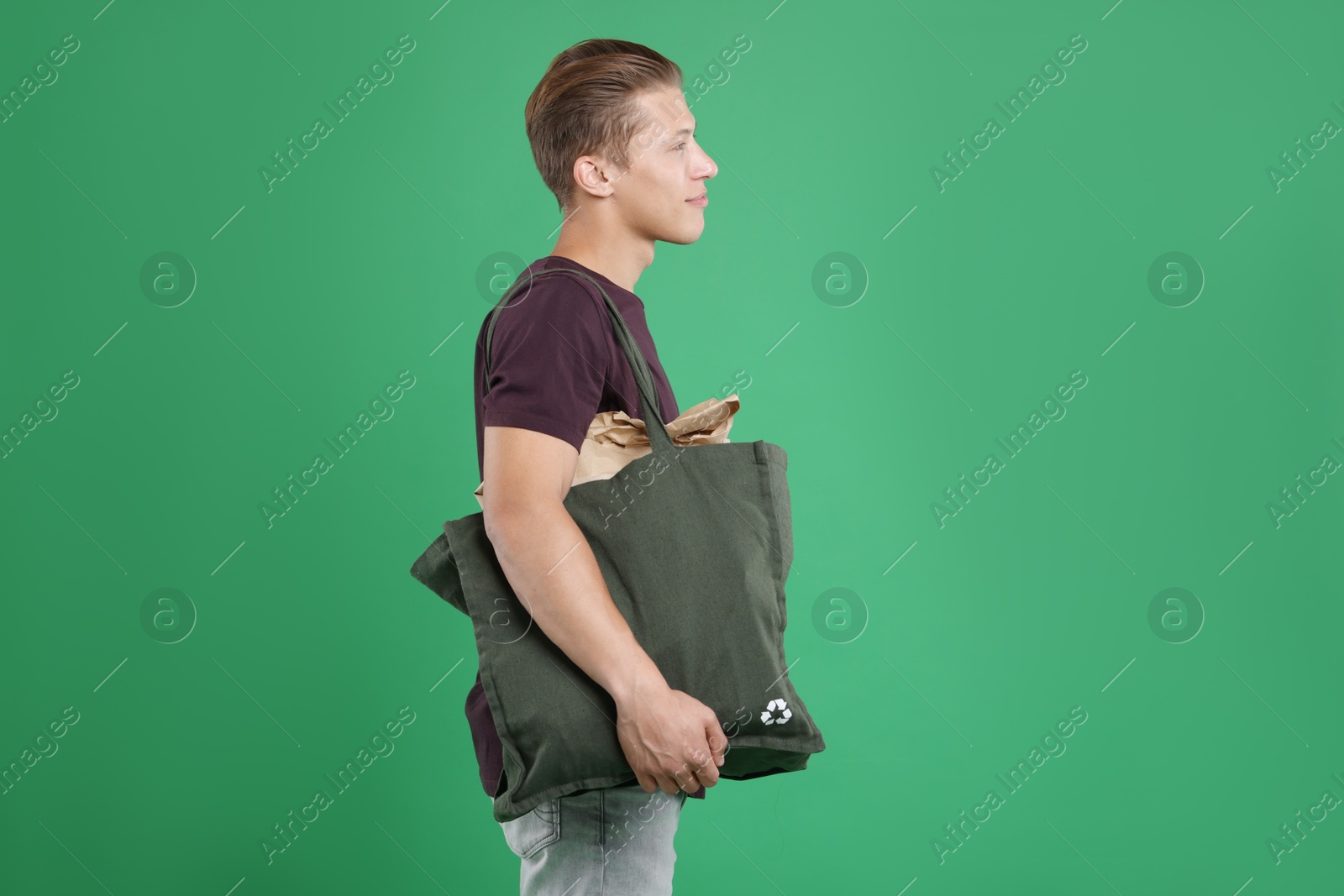 Photo of Recycling. Man with bag full of different waste paper on green background