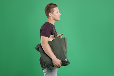 Photo of Recycling. Man with bag full of different waste paper on green background