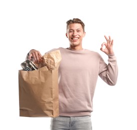 Photo of Recycling. Smiling man with bag full of different waste paper showing OK gesture on white background