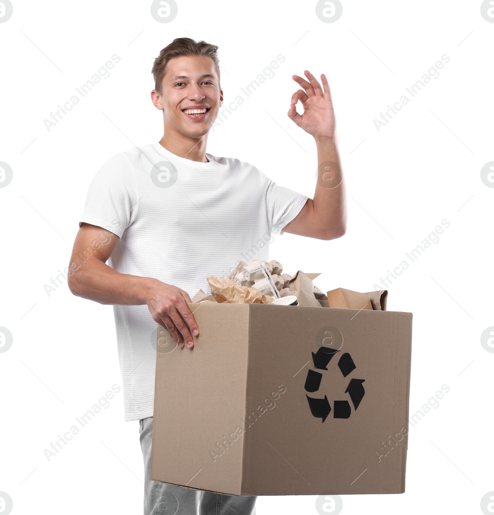 Recycling. Smiling man holding cardboard box with different waste paper and showing OK gesture on white background Photo of Recycling. Smiling man holding cardboard box with different waste paper and showing OK gesture on white background