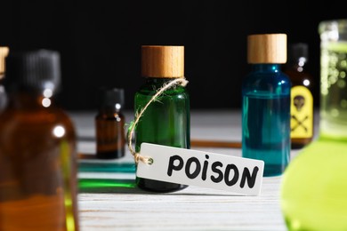 Photo of Bottles with poisons on wooden table against black background, closeup