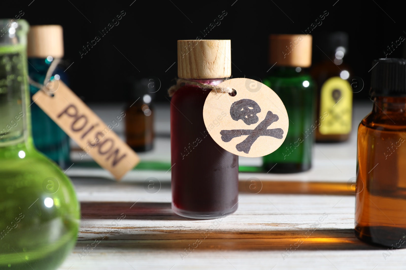 Bottles of poisons with warning sign on wooden table against black background, closeup Photo of Bottles of poisons with warning sign on wooden table against black background, closeup