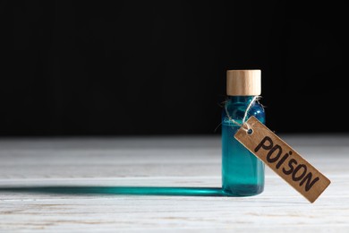 Photo of Bottle with poison on wooden table against black background, space for text