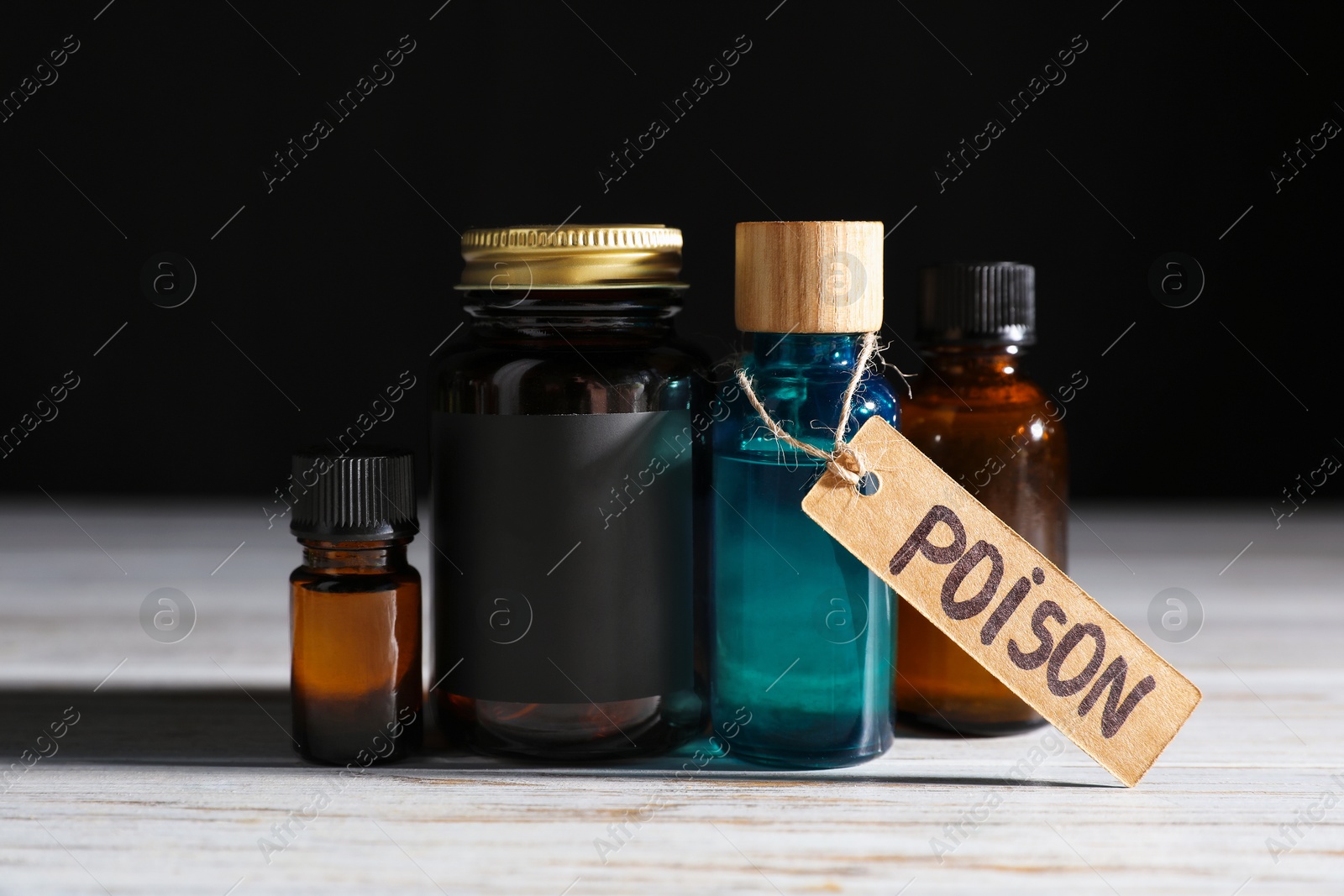 Bottles with poisons on wooden table against black background, closeup Photo of Bottles with poisons on wooden table against black background, closeup