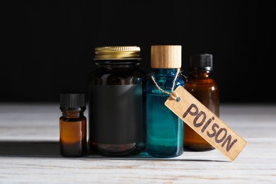 Photo of Bottles with poisons on wooden table against black background, closeup