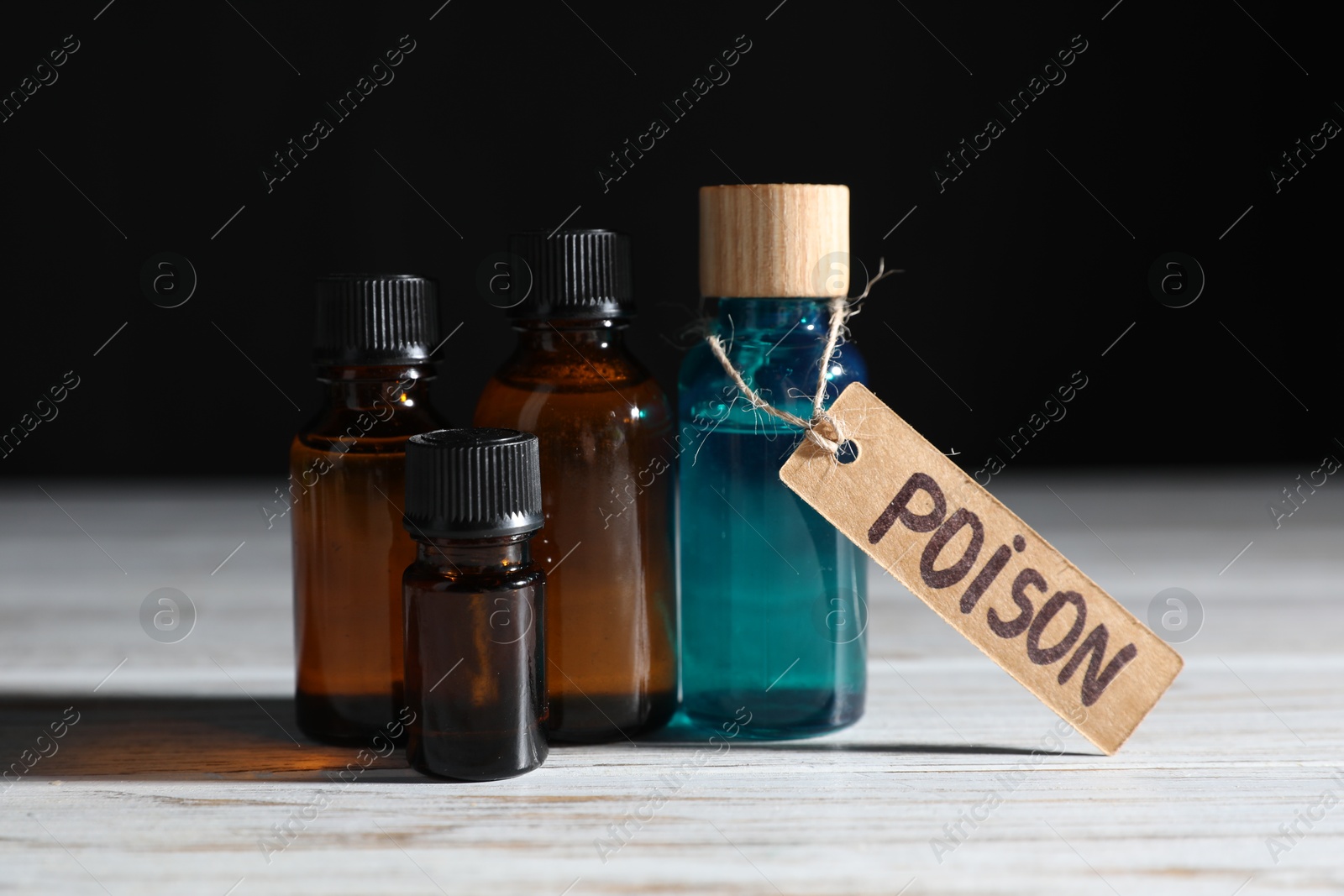Bottles with poisons on wooden table against black background, closeup Photo of Bottles with poisons on wooden table against black background, closeup
