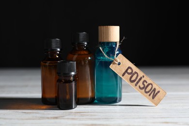 Photo of Bottles with poisons on wooden table against black background, closeup