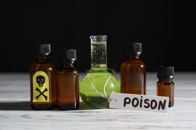 Photo of Bottles with poisons on wooden table against black background