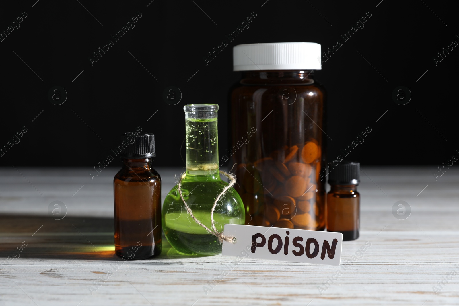Photo of Bottles with poisons on wooden table against black background