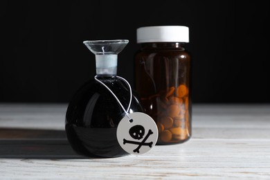 Photo of Bottles of poisons with warning sign on wooden table against black background, closeup