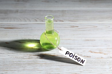 Photo of Flask with poison on wooden table, closeup