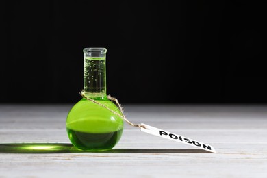 Photo of Flask of poison on wooden table against black background