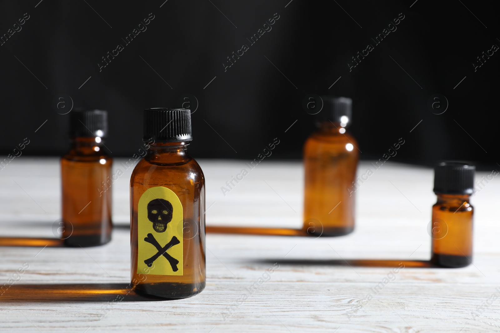 Bottles of poisons with warning sign on wooden table against dark background, closeup Photo of Bottles of poisons with warning sign on wooden table against dark background, closeup
