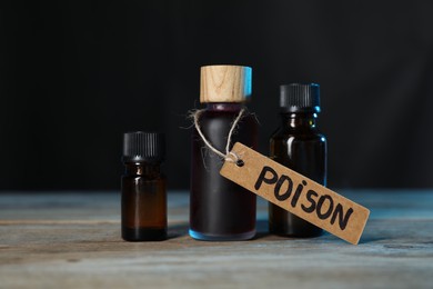 Photo of Bottles of poisons on wooden table against dark background, closeup