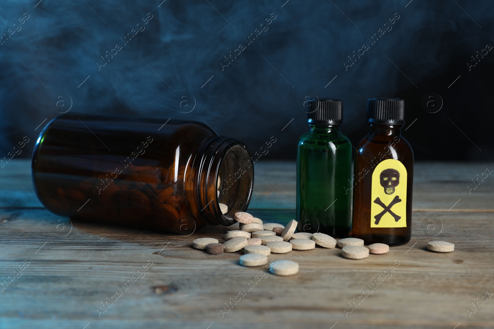 Photo of Bottles of poisons with warning sign on wooden table against dark background with smoke, closeup