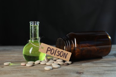 Photo of Bottles of poisons on wooden table against dark background, closeup