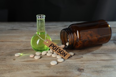 Photo of Bottles of poisons on wooden table against dark background, closeup
