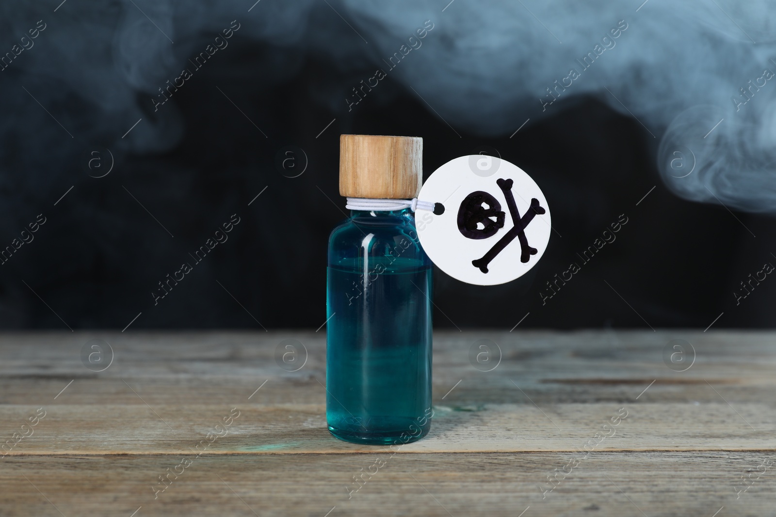 Photo of Bottle of poison with warning sign on wooden table against dark background with smoke