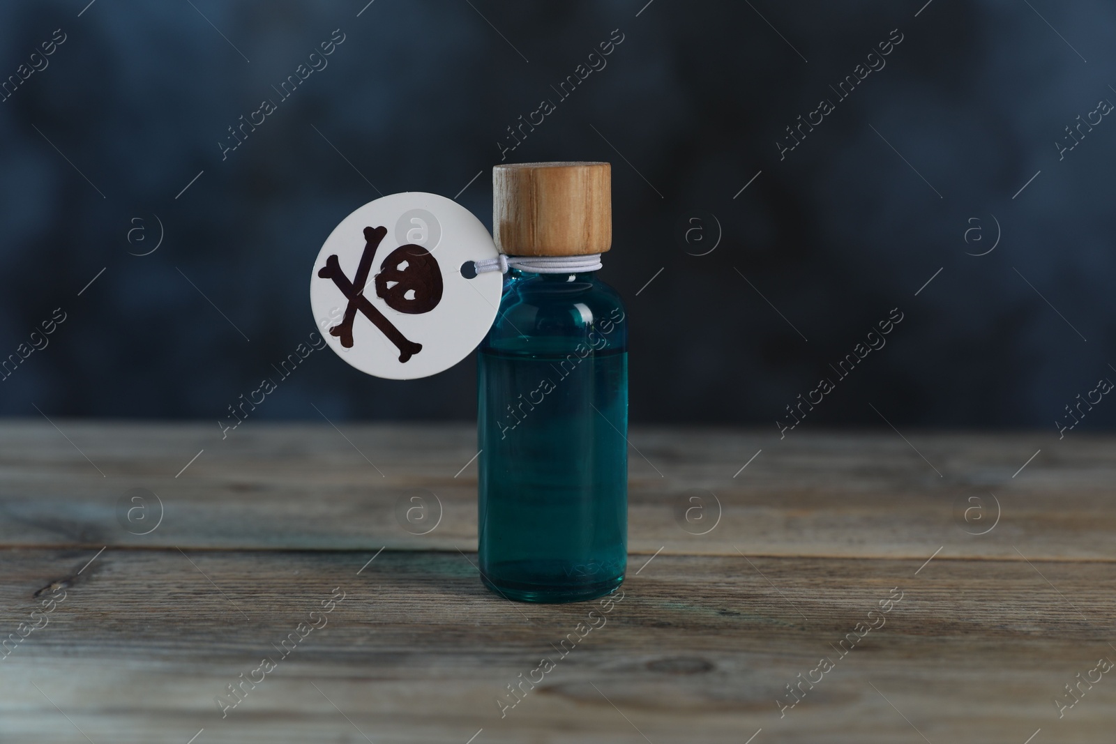 Photo of Bottle of poison with warning sign on wooden table against dark background with smoke