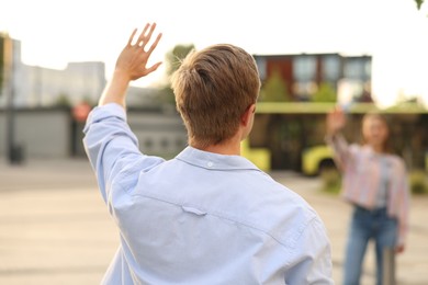 Photo of Goodbye. Man waving to his girlfriend outdoors, selective focus