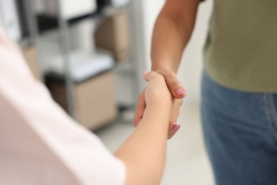 Photo of Cooperation. Women shaking hands in office, closeup