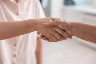 Photo of Cooperation. Women shaking hands in office, closeup