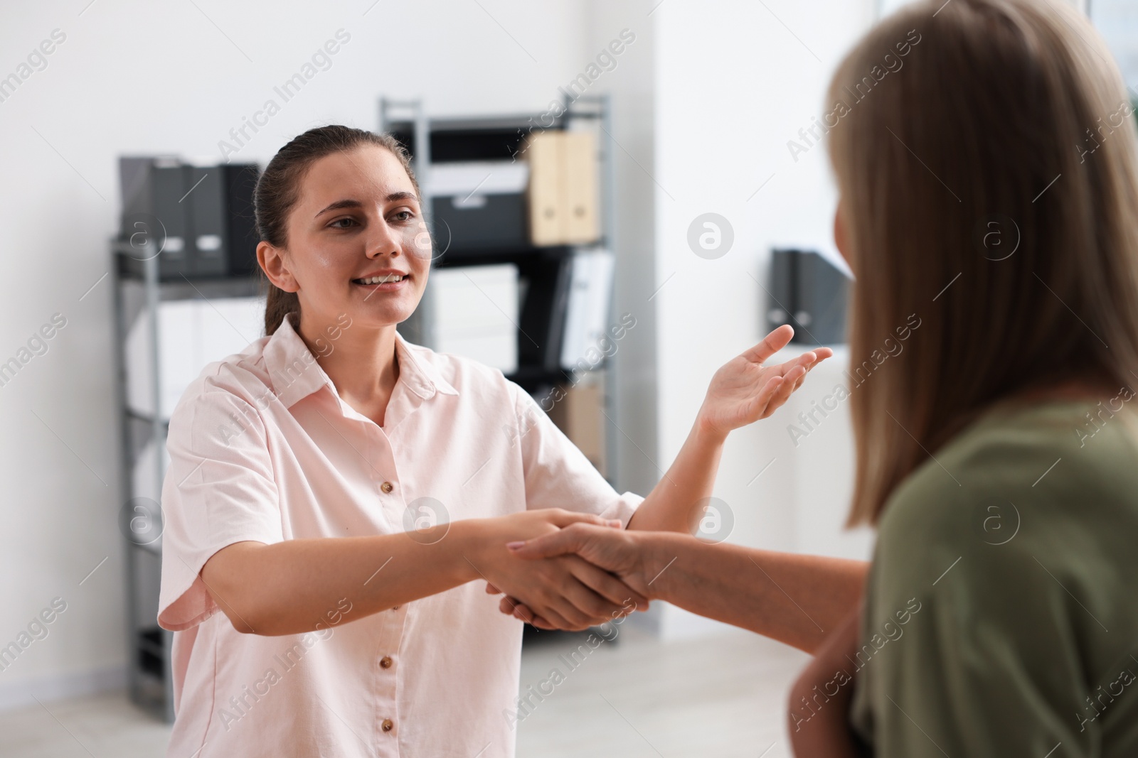 Photo of Cooperation and teamwork. Women shaking hands in office