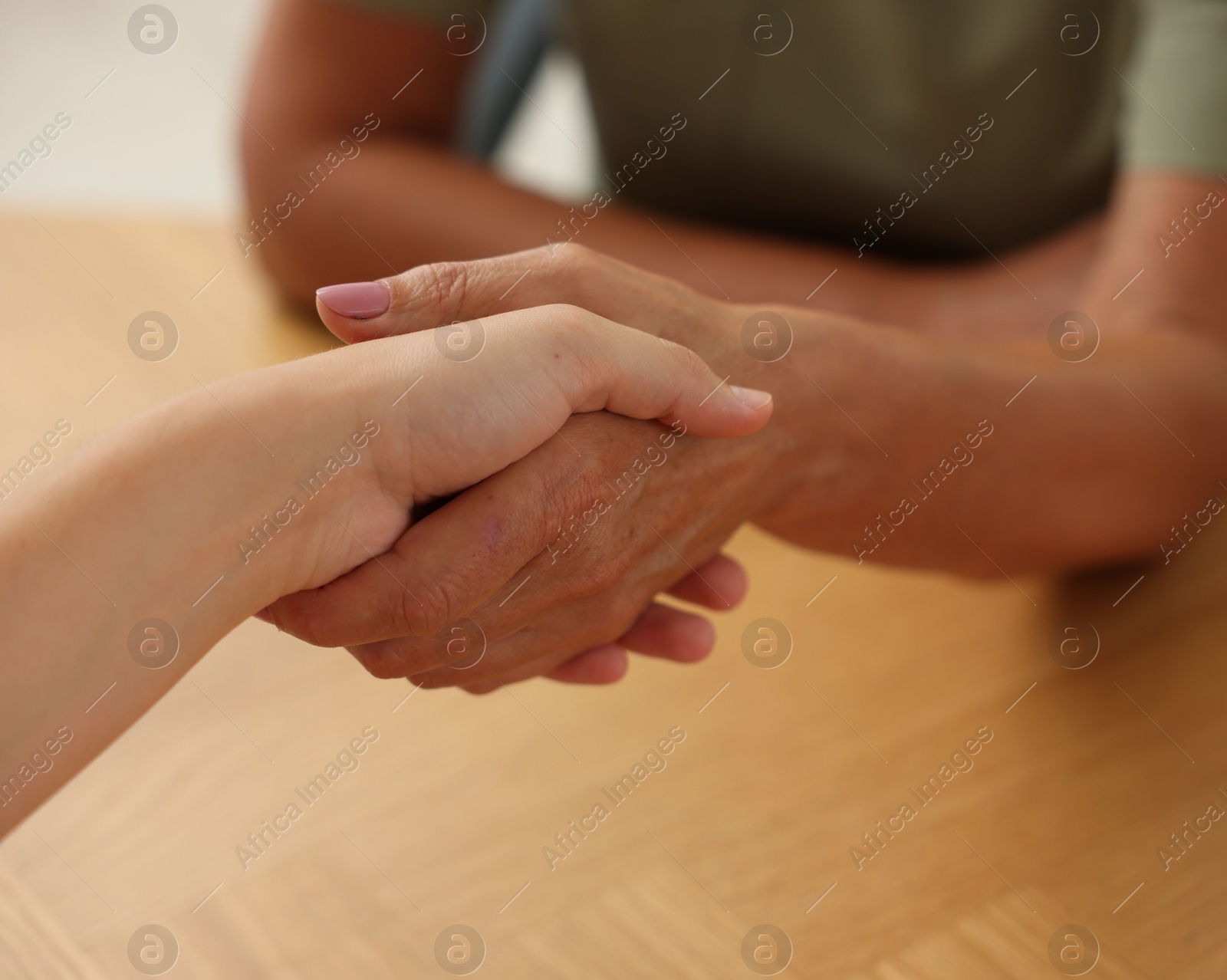 Photo of Women shaking hands at wooden table in office, closeup
