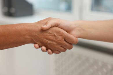Photo of Cooperation. Women shaking hands in office, closeup