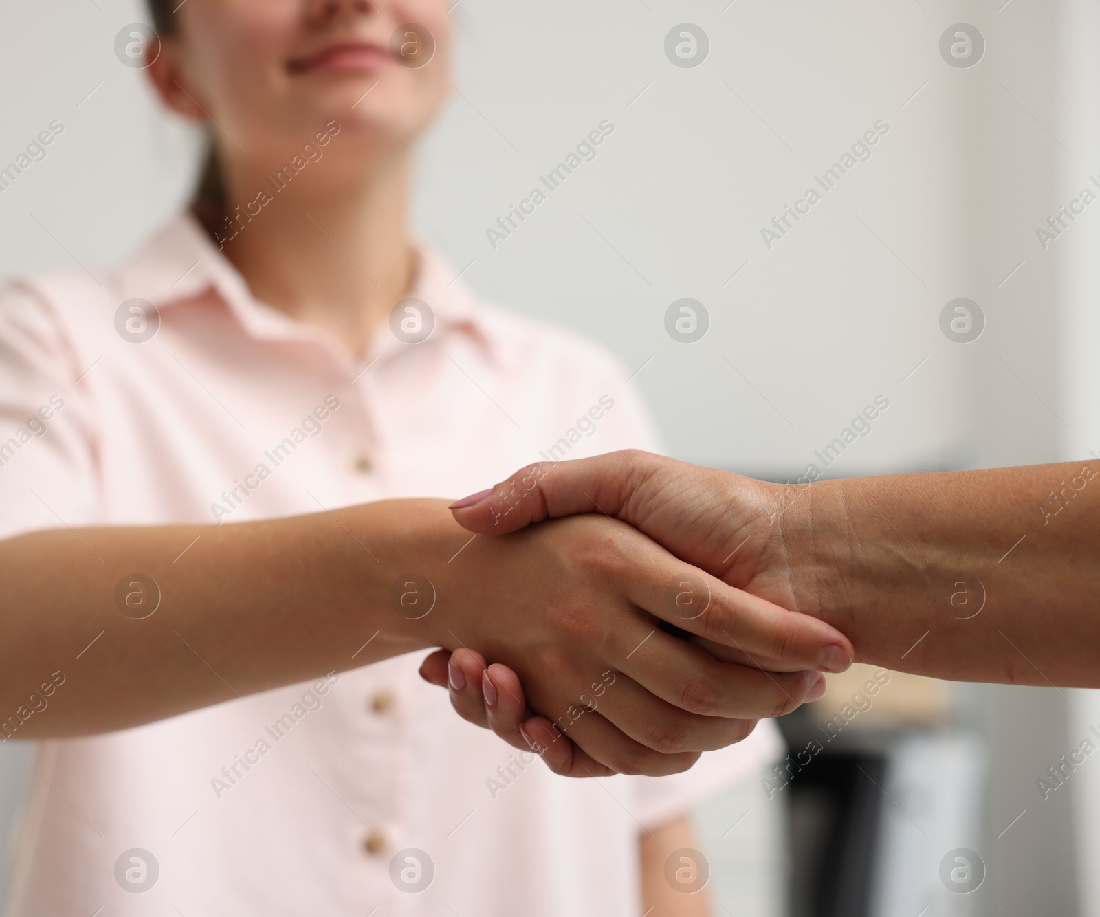 Photo of Cooperation. Women shaking hands in office, closeup