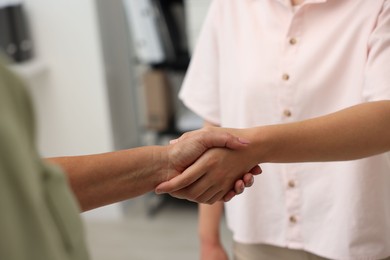 Photo of Cooperation. Women shaking hands in office, closeup